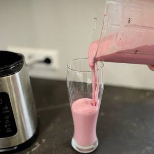 Eine Person schenkt aus dem getesteten Standmixer einen Milchshake in ein Glas.