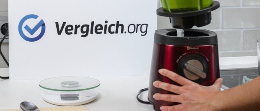 Standmixer wird aufgestellt vor einem Schild mit dem Schriftzug Vergleich.org