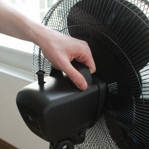 Ein Ventilator wird an seinem Tragegriff hochgehoben.
