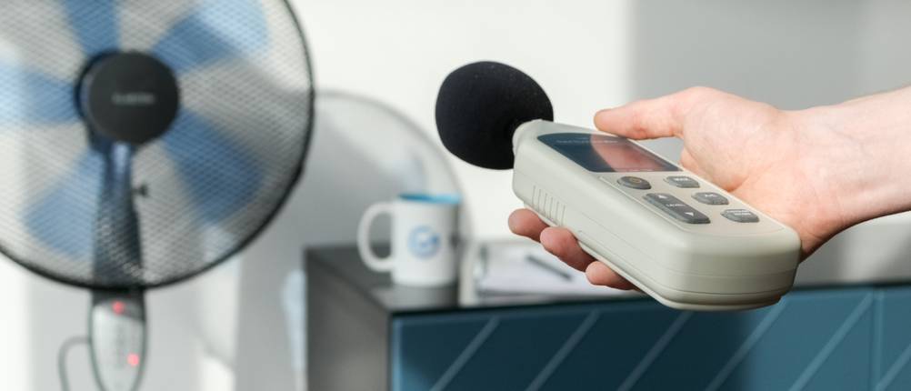 Mit einem Lautstärke-Messgerät wird ein Standventilator untersucht.