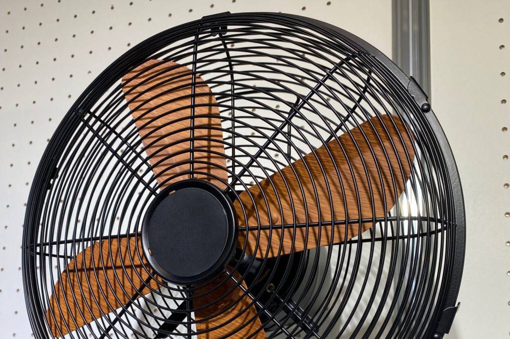 Getesteter Standventilator mit Holzflügeln befindet sich auf einer weißen Oberfläche.
