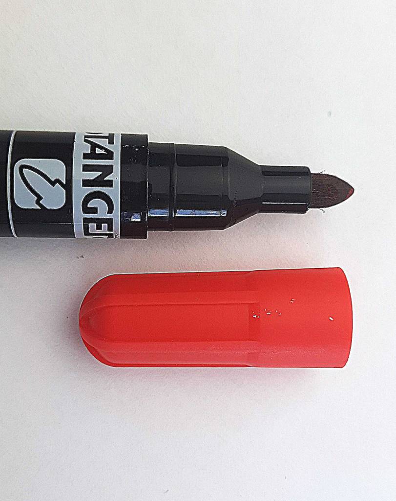 Auf einer weißen Oberfläche liegt der getestete Alkoholmarker neben seiner roten Verschlusskappe.