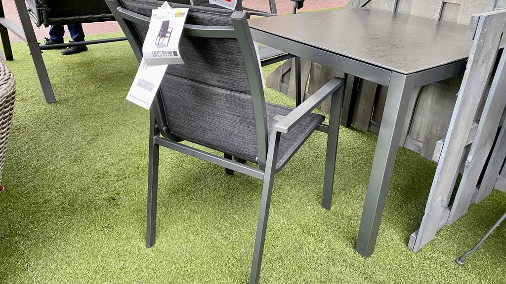 Mehrere getestete Stapelstühle befinden sich an einem Gartentisch. 