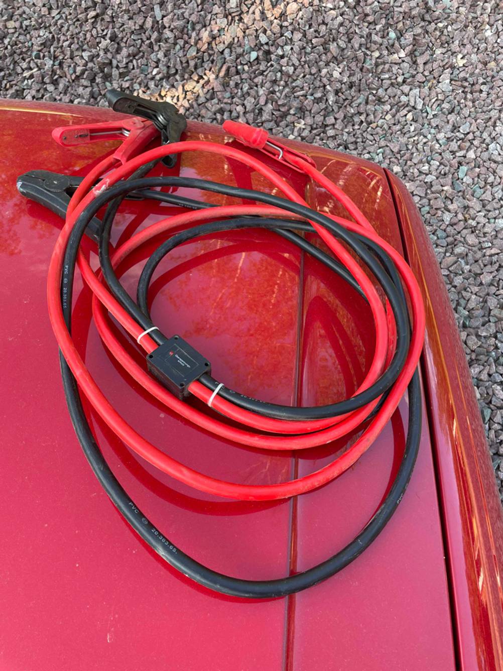 Ein getestetes Starthilfekabel liegt auf dem Auto.