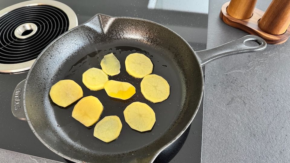 Staub-Gusseisenpfanne mit Kartoffeln auf dem Kochfeld