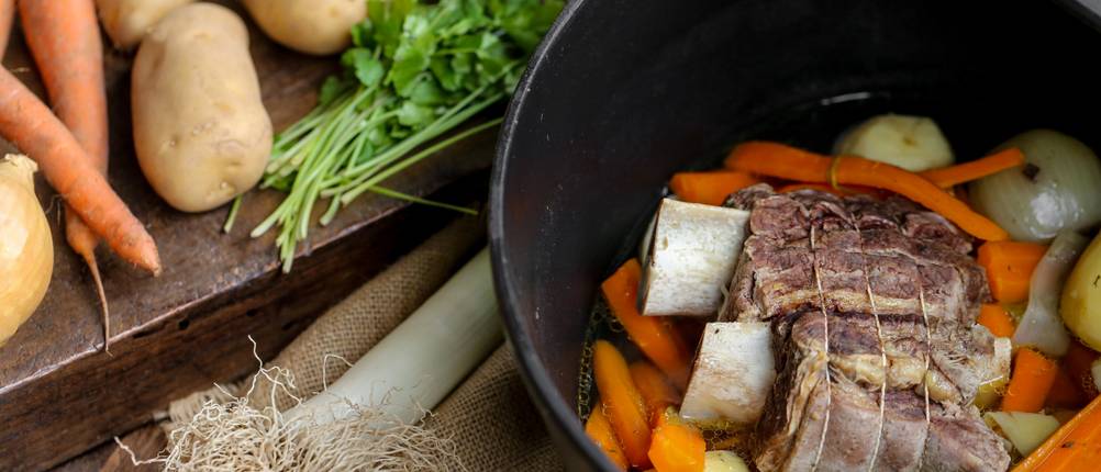 STAUB-Bräter im Test: Bräter befüllt mit einem Braten und frischem Gemüse, daneben auf der Ablage weiteres Gemüse