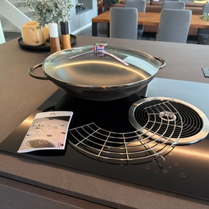 Der Lieferumfang vom Staub-Wok liegt auf einer Kochplatte