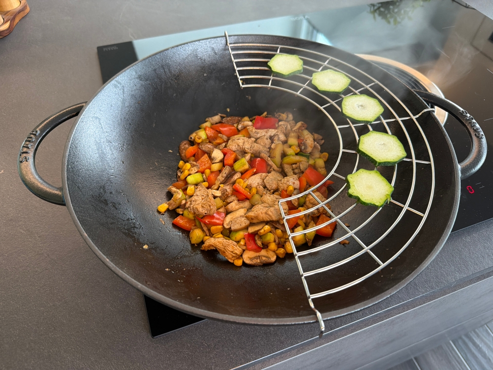 Zucchinischeiben liegen auf einem Aufsatz im Staub-Wok