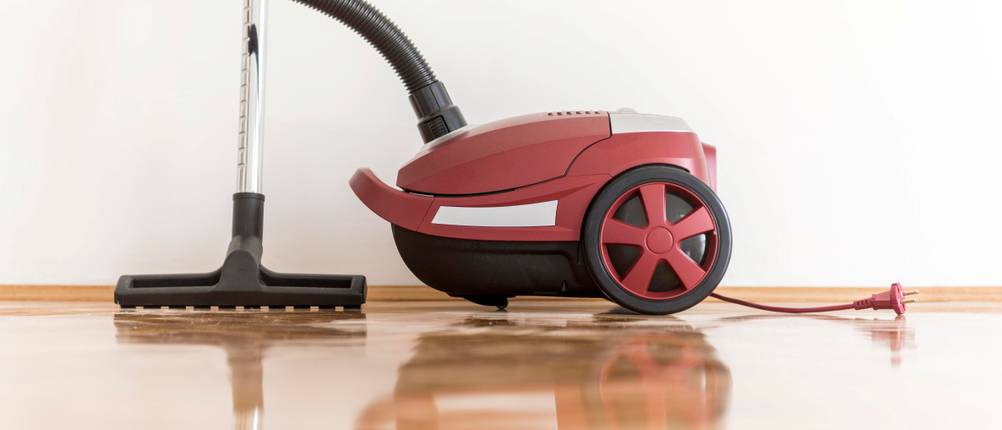 Staubsauger mit Beutel im Test: roter Staubsauger steht auf Parkett