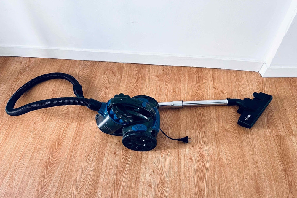 Staubsauger steht auf dem Holzboden.
