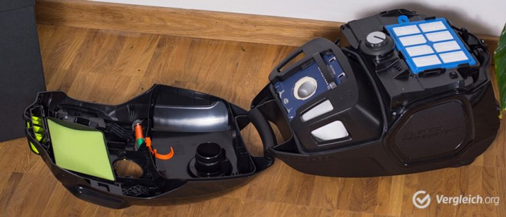 Aufgeklappter Staubsauger im Test auf einem Parkettboden.