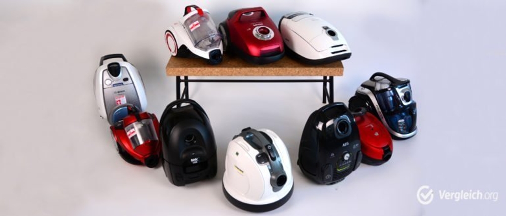 Mehrere Staubsauger stehen auf und um einen Tisch.