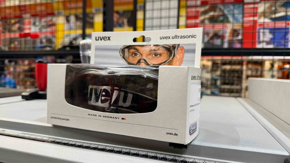 Die getestete Staubschutzbrille in der Verpackung auf einer hellen Fläche stehend.