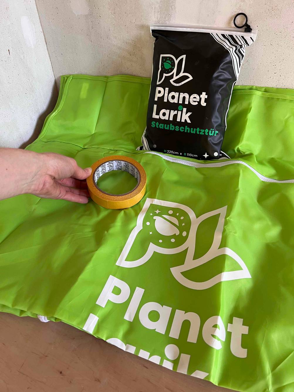 Staubschutztür getestet: Auf der ausgepackten Staubschutztür legt eine Hand ein Klebeband.