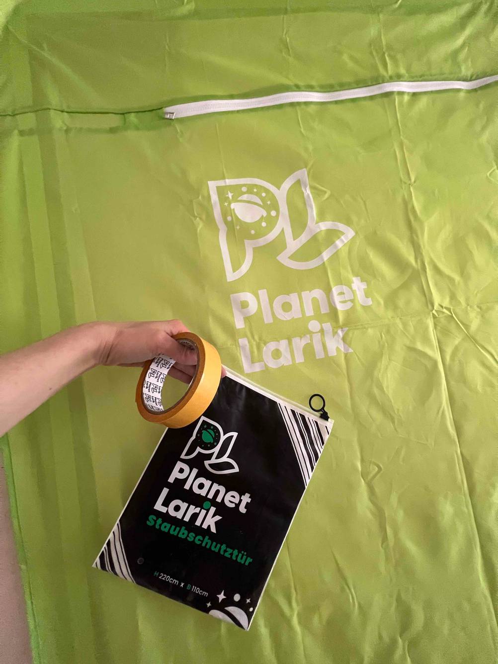Eine Hand hält die Verpackung und ein Klebeband vor die getestete Staubschutztür.