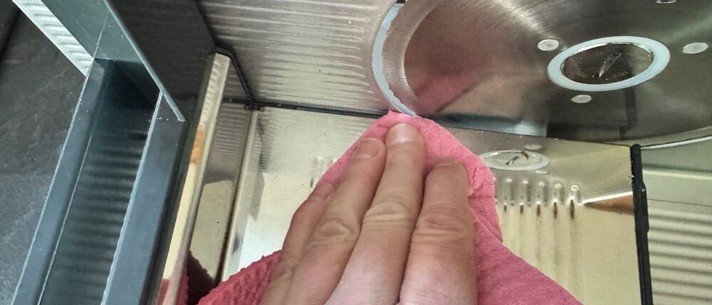 Eine Hand reinigt das Messer des Steba 291000 mit einem Lappen