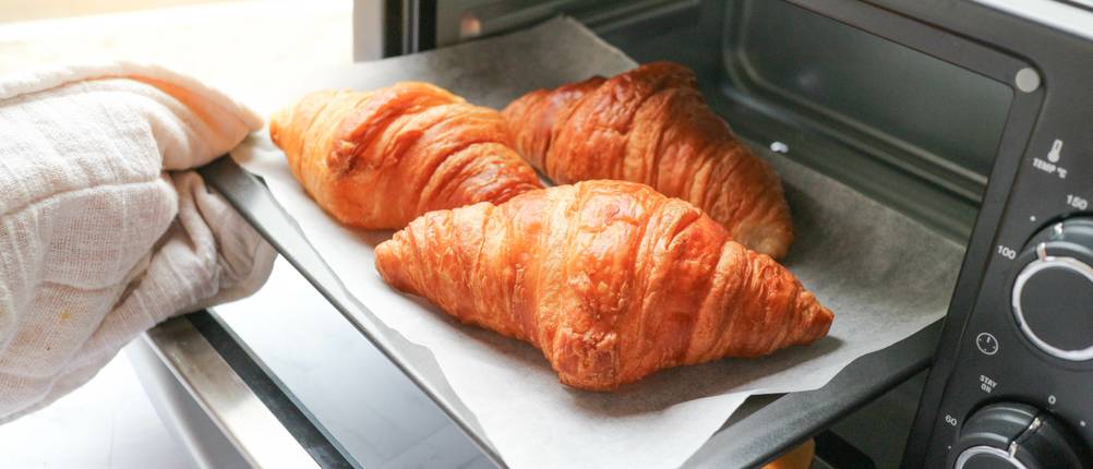 Steba-Minibackofen Test: drei Croissants im offenen Backofen auf mit Backpapier belegtem Blech