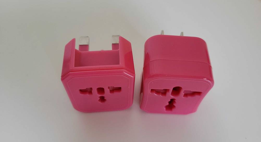 Zwei unterschiedliche Steckdosenadapter im Test von schräg oben auf einer hellen Fläche.