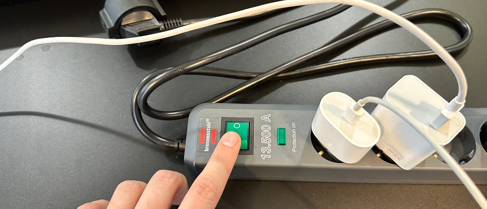 Ein Finger drückt den grünen Hauptschalter der Brennenstuhl-Eco-Line-Steckdosenleiste.