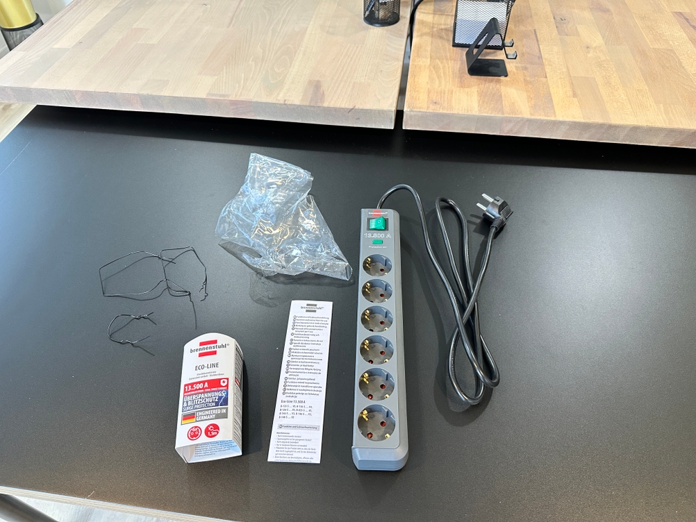 Die Brennenstuhl-Eco-Line-Steckdosenleiste und der zugehörige Lieferumfang liegen vollständig ausgelegt auf dem Tisch.