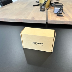 Die Verpackung der JSVER-PS3132-Würfelsteckdose steht auf einem schwarzen Tisch.