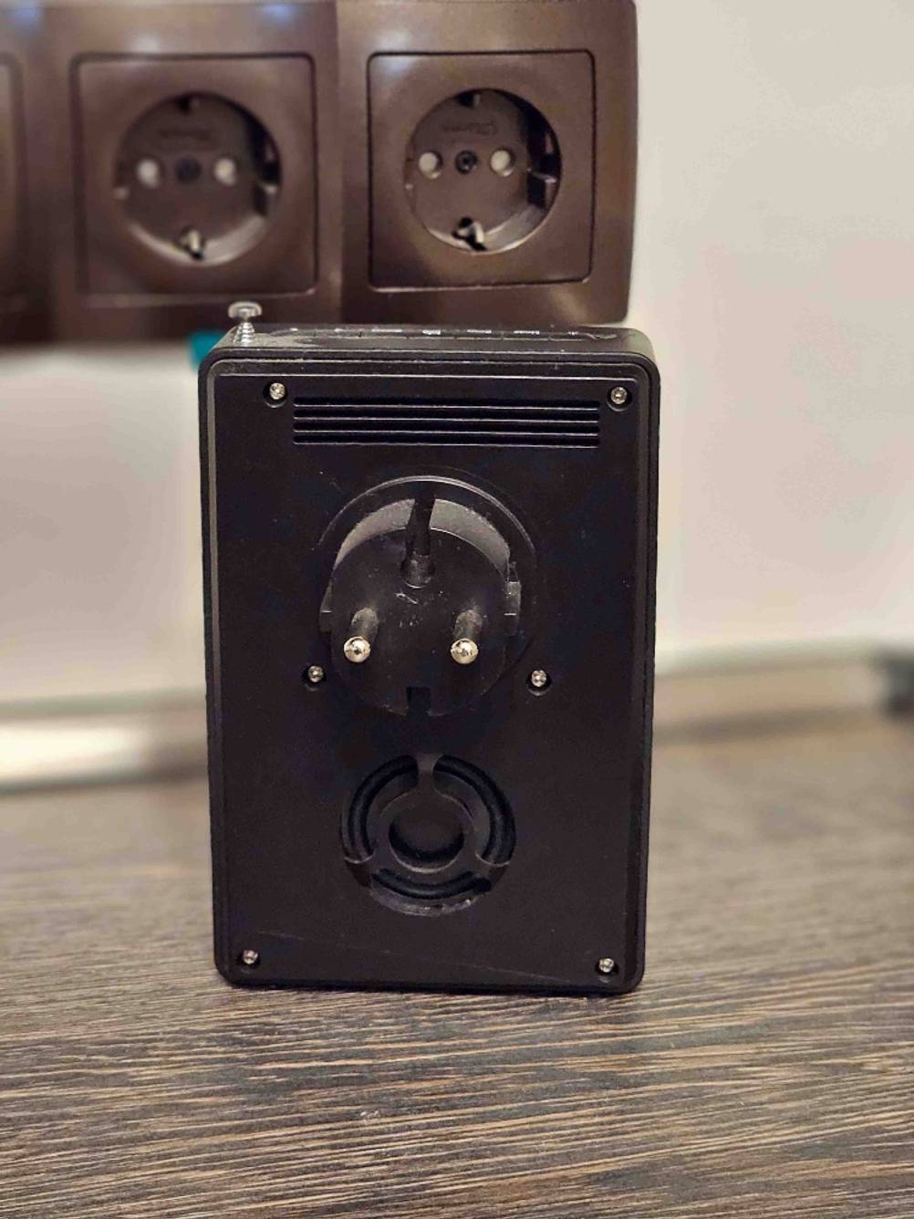 Getestet: Ein Steckdosenradio von hinten mit dem Stecker in Nahaufnahme im Hintergrund eine Steckdosenleiste.