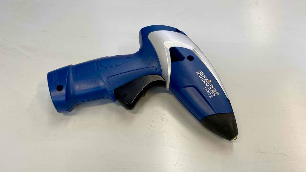 Im Test: Eine Akku-Heißklebepistole auf einer hellen Fläche liegend.