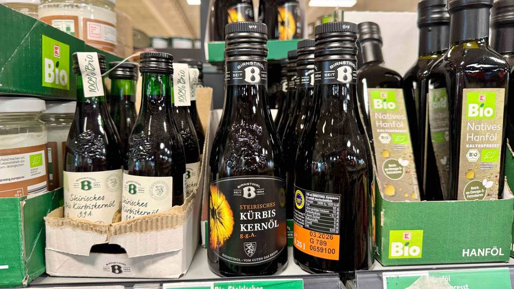 Getestet: Mehrere Flaschen des steirischen Kürbiskernöls in einem Regal neben anderen Produkten.