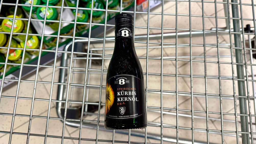 In einem Einkaufswagen liegt eine Flasche des getesteten steirischen Kürbiskernöl.