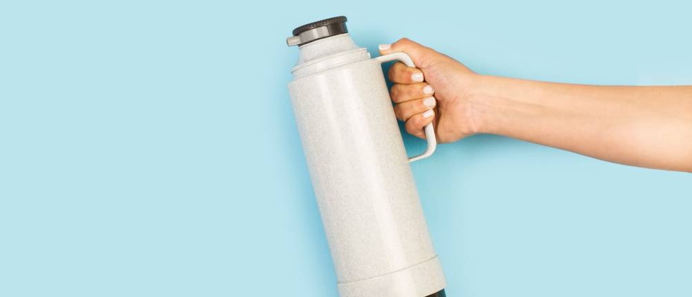 Stelton-Isolierkanne im Test: Beige Isolierkanne vor hellblauem Hintergrund.