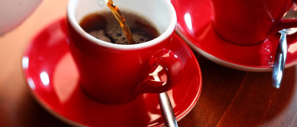 Stelton-Isolierkanne im Test: Kaffee wird in rote Tassen gegossen