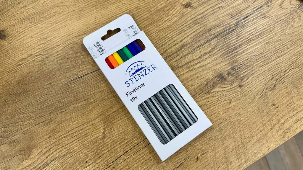 Eine 10-Stück-Packung mit Finelinern im Test liegt auf einer Holzoberfläche.