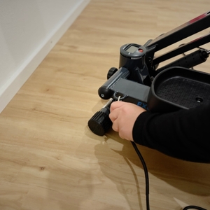 Eine Hand benutzt ein Werkzeug, um eine Einstellschraube am Fuß des Steppers zu justieren.