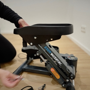 Eine kniende Person justiert mit der Hand eine Seite des hochgezogenen Trittbretts.