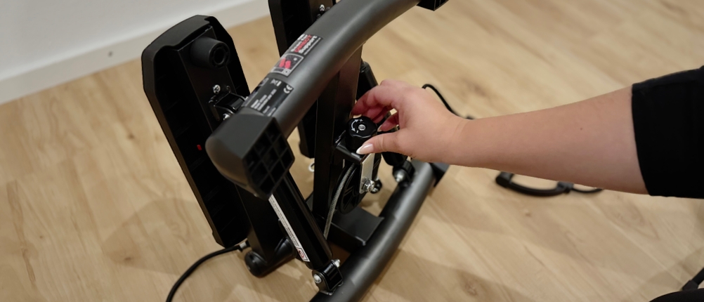 Eine Hand, die einen schwarzen Knopf am zentralen Rahmen eines Mini-Steppers dreht.