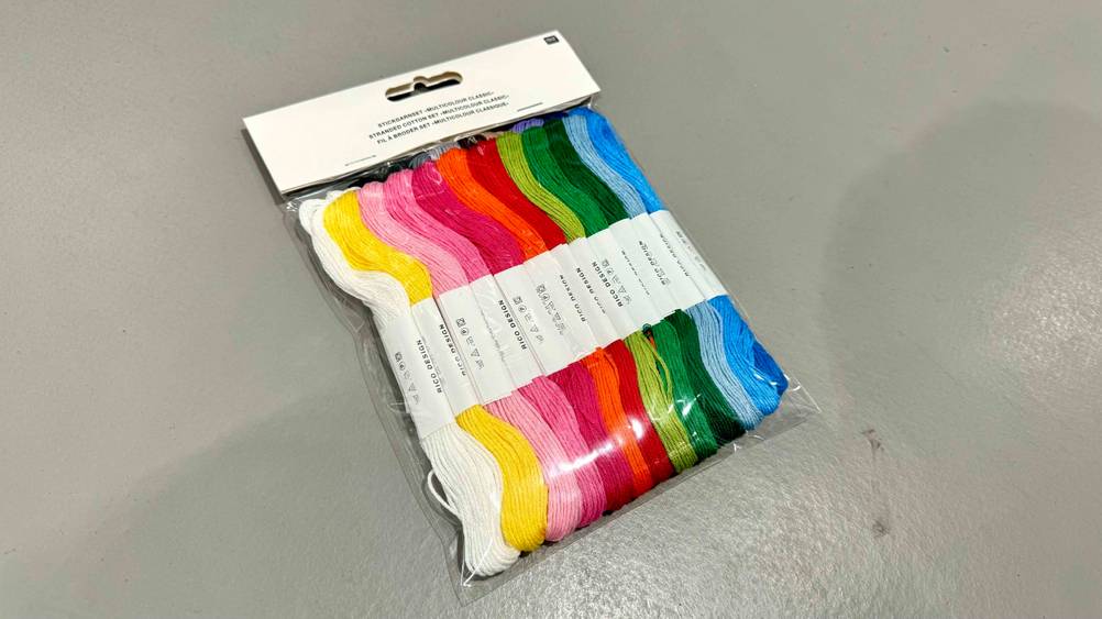 Das transparent verpackte Stickgarn im Test auf einer grauen Fläche liegend.