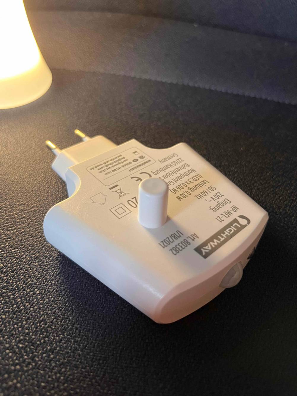 Nahaufnahme des Stromsteckers eines Stilllichtes auf einer dunklen Fläche.