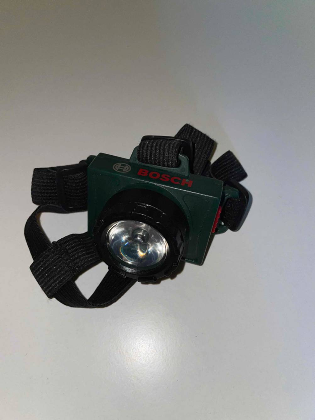Stirnlampe (Kinder) im Test: Eine Lampe von schräg oben auf einer hellen Fläche.