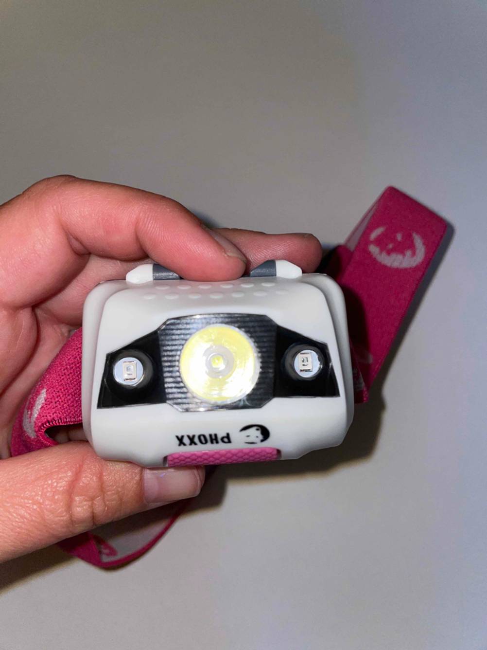 Nahaufnahme der Lampe einer getesteten Stirnlampe von einer Hand gehalten.