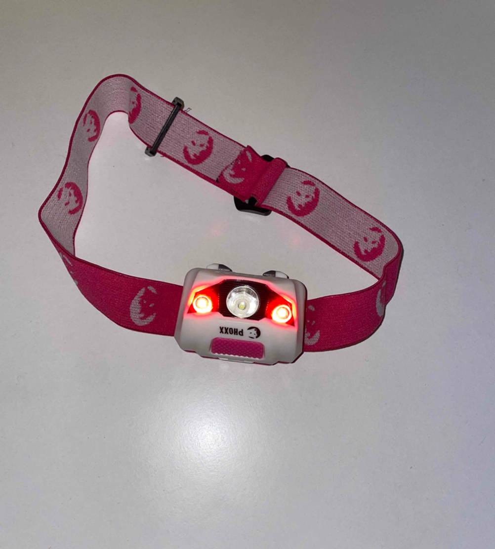 Eine getestete Stirnlampe mit Kopfband von oben auf einer weißen Fläche.