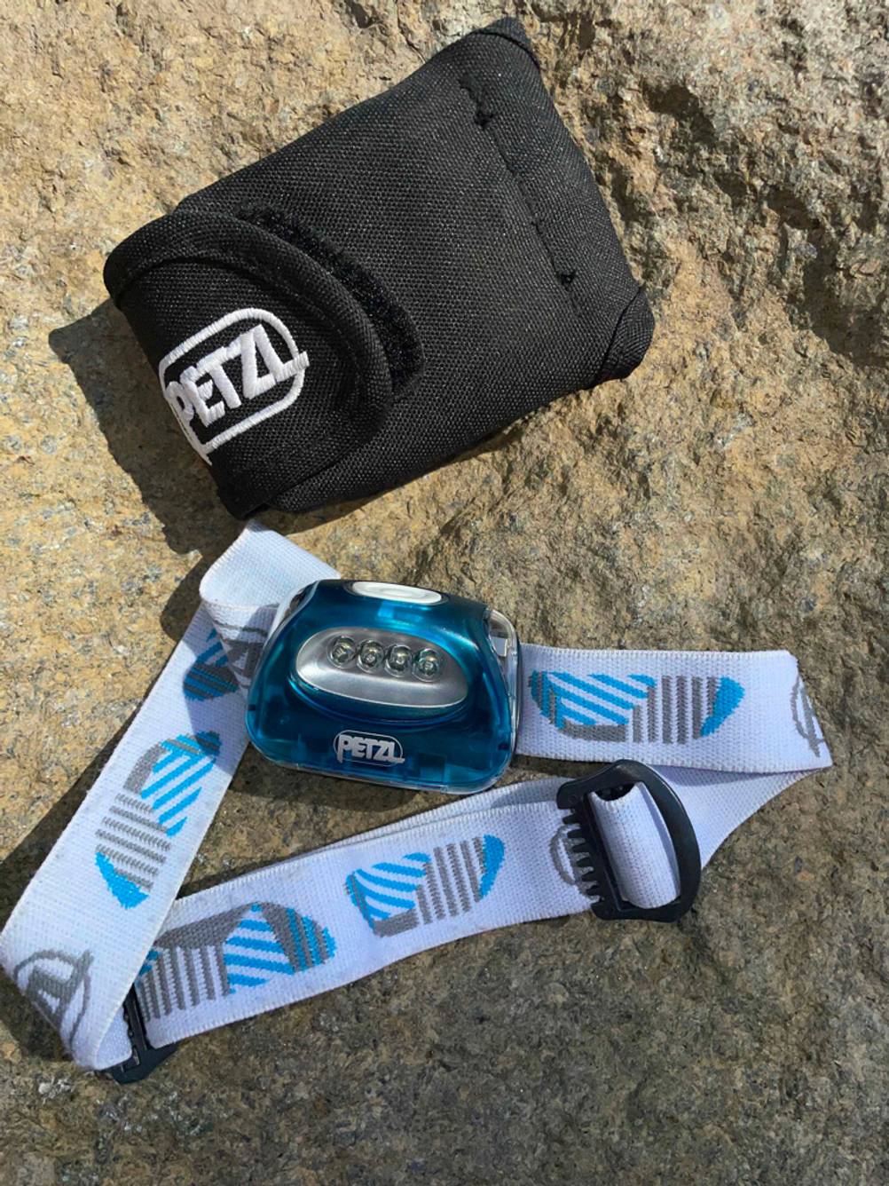 Petzl-Stirnlampen-Test: Eine Stirnlampe von Petzl mit Aufbewahrungstasche liegt auf einem Stein.