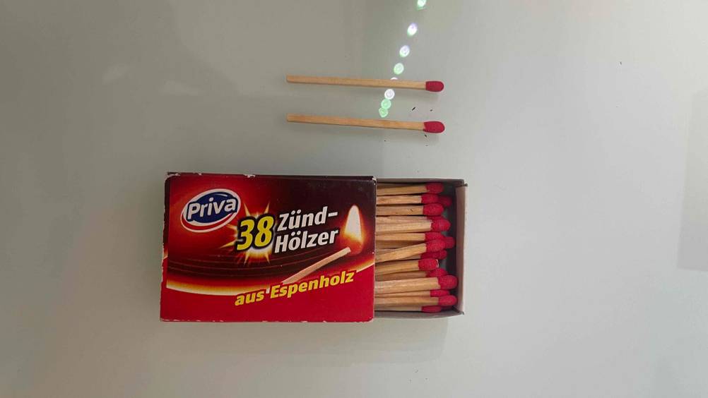 Über der geöffneten Streichholzschachtel liegen zwei Streichhölzer im Test.