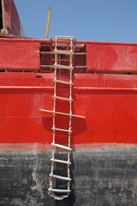 Strickleiter-Test: Eine Holz-Strickleiter an einem roten Schiff. 
