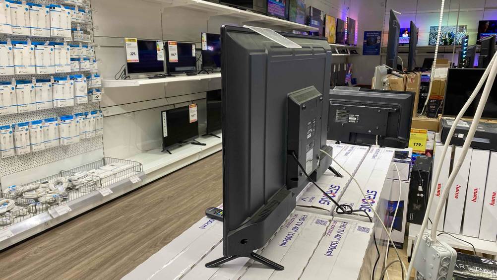 Rückseite eines 40-Zoll-Fernsehers im Test der auf mehreren verpackten Geräten steht, im Hintergrund andere Geräte.