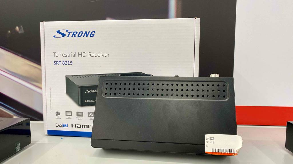 Ein getesteter DVB-T-Receiver lehnt mit Blick auf die Oberseite an den Originalkarton.