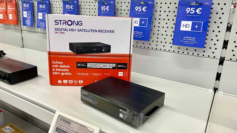 Im Test: Ein HD-Sat-Receiver steht vor seiner aufgestellten Originalverpackung auf einem hellen Regal.