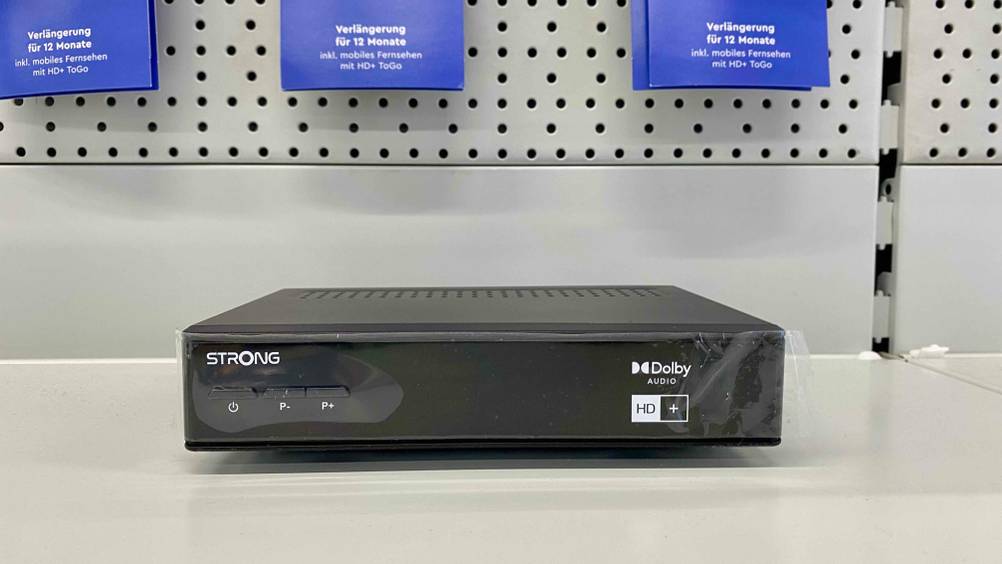 Ein HD-Sat-Receiver im Test von vorne auf einer hellen Fläche.
