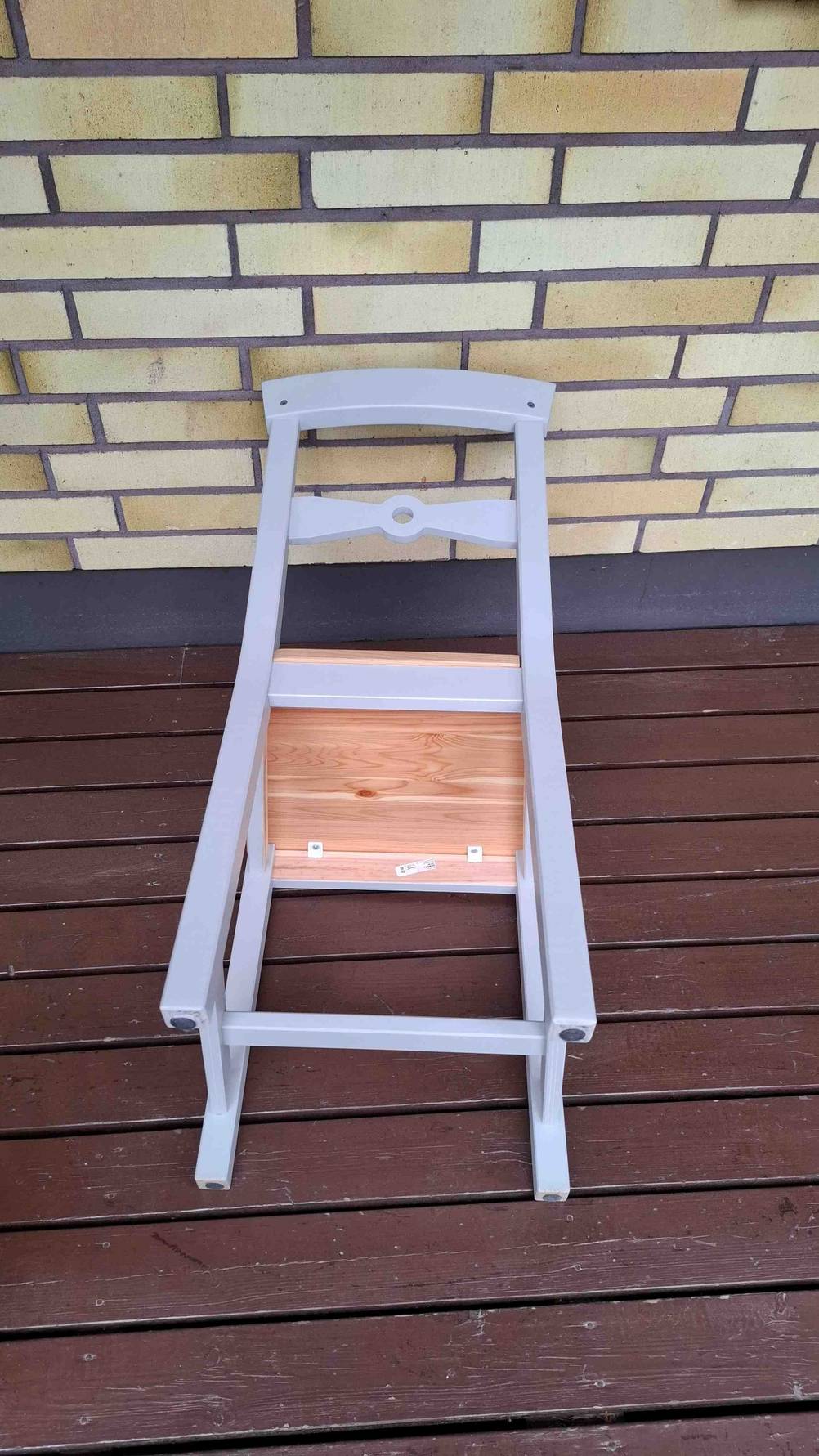 Im Test: Ein Stuhl liegt mit der Lehne nach oben auf einem Dielenboden.