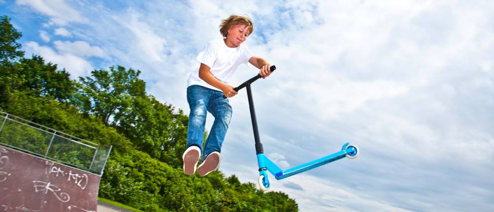 Stunt-Scooter im Test: Junge, der mit seinem Stunt-Scooter einen Sprung durchführt
