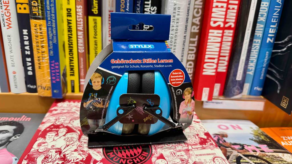 Ein getesteter Kinder-Gehörschutz steht verpackt vor einem Bücherregal.